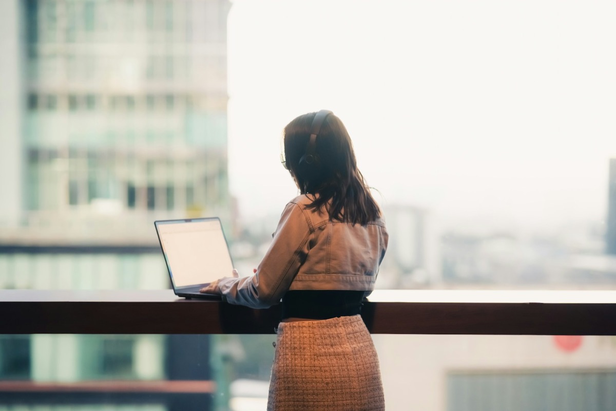 An engineer working on a laptop by a window overlooking a city